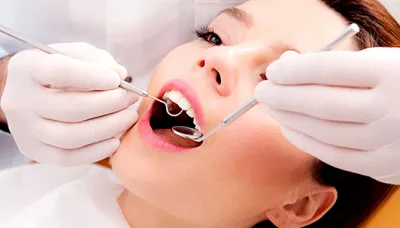 девушке в стоматологическом кресле врач осматривает зубы